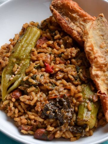 This is a photo of Guyanese cookup rice in a white bowl served with ochro and fried fish and mango achar