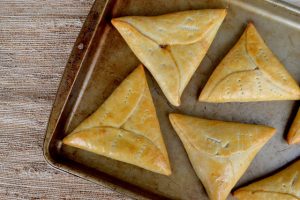 The image is a triangle shaped pine tart on a baking sheet