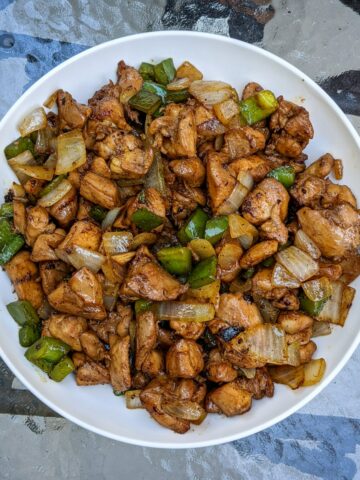 This is a photo of small pieces of black pepper chicken cut up and in a white bowl.