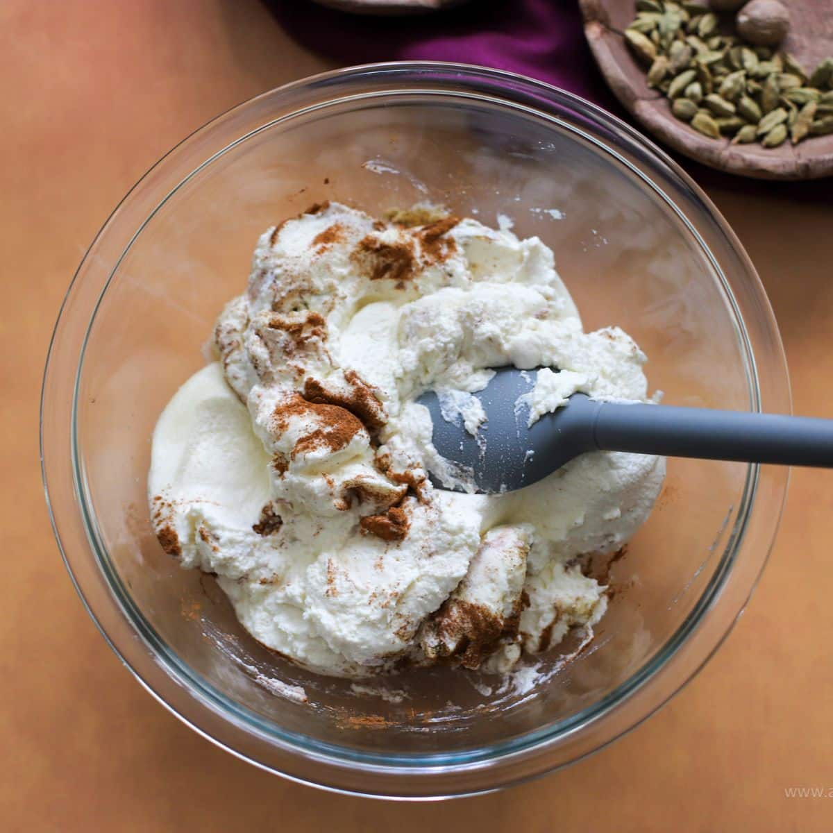 rasmala cheese mixture in a glass bowl with cinnamon and cardamom on top