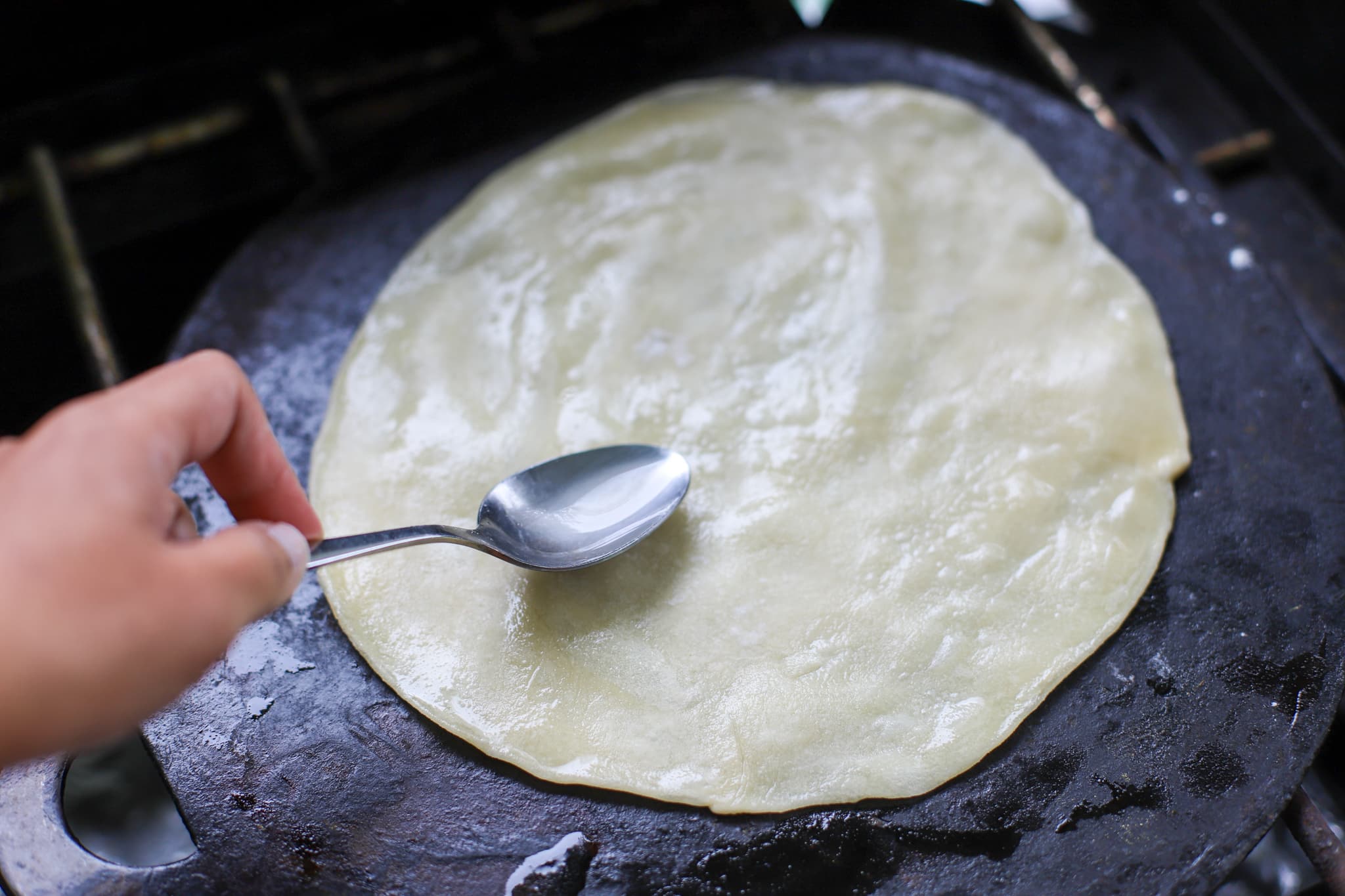 spreading oil on the roti on the tawa