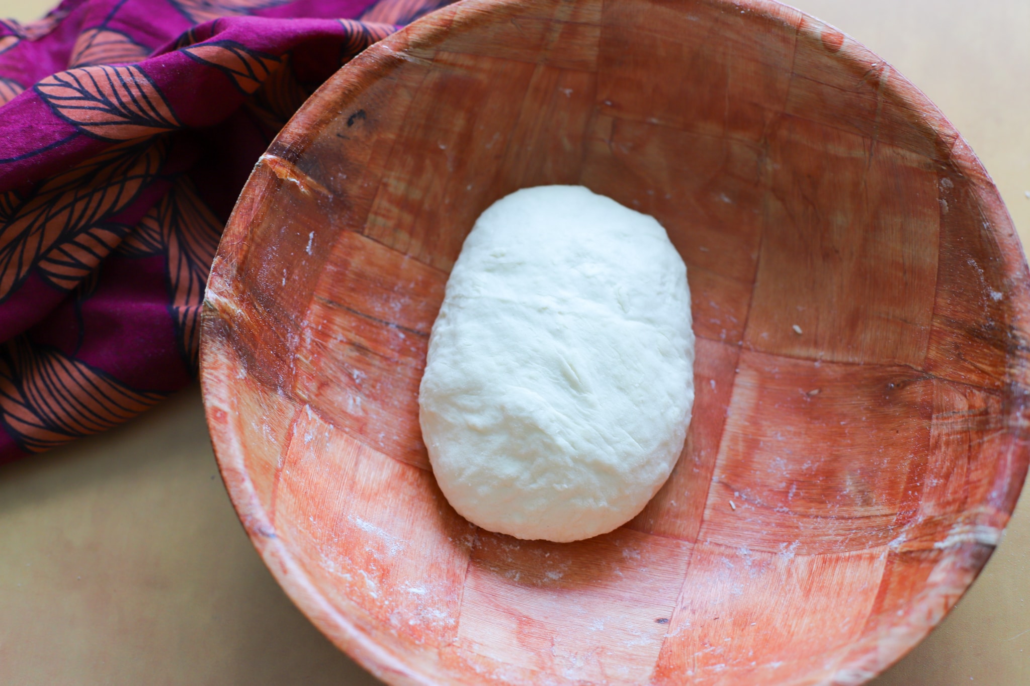 A wooden bowl with kneaded dough ball for guyanese oil roti