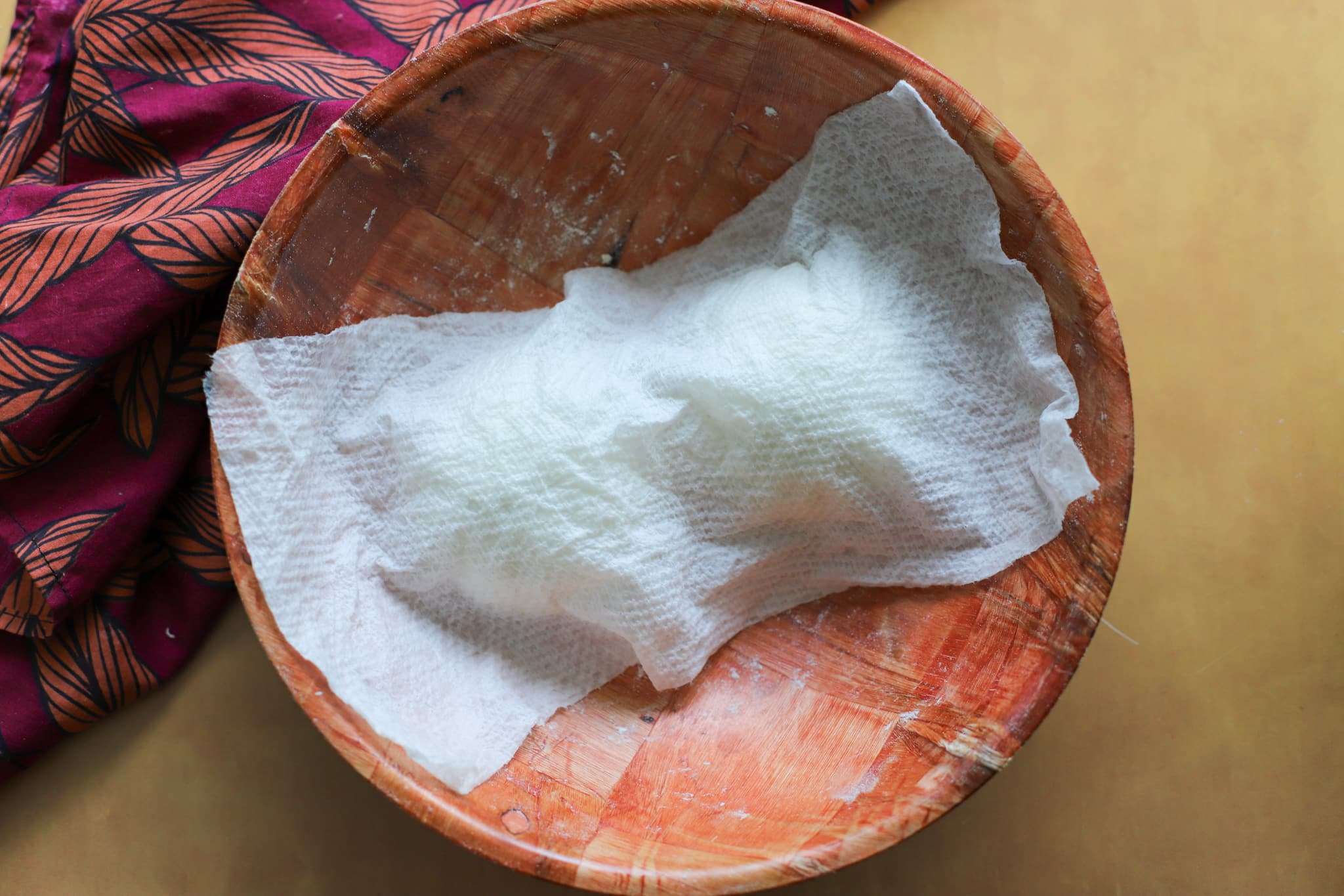 wooden bowl with two dough balls and damp paper towels covering the dough balls