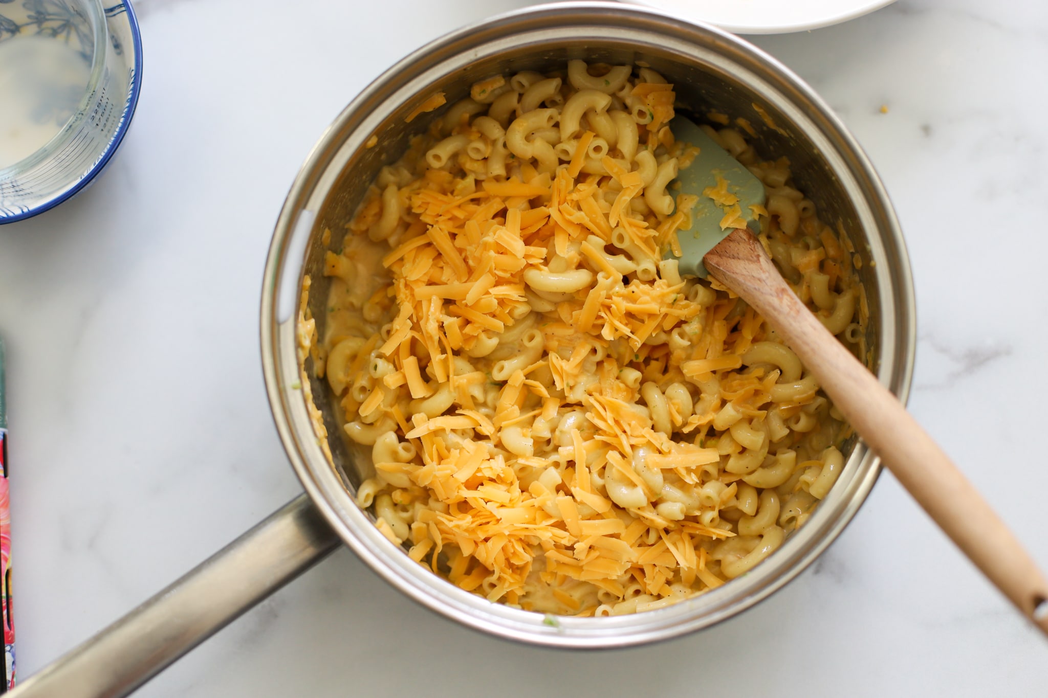 mixture for macaroni pie in a pot with more cheee sprinkled on top