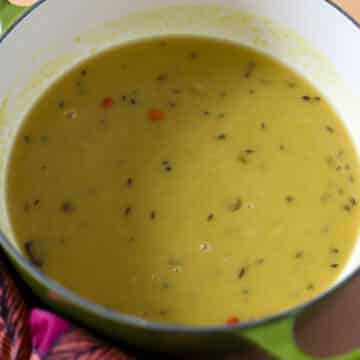 This is a pot of stovetop indo-caribbean style dhal it is in a green cast iron pot with a pink napkin next to it