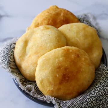 this photo shows 4 fried bakes golden brown and in a black and white decorative napkin