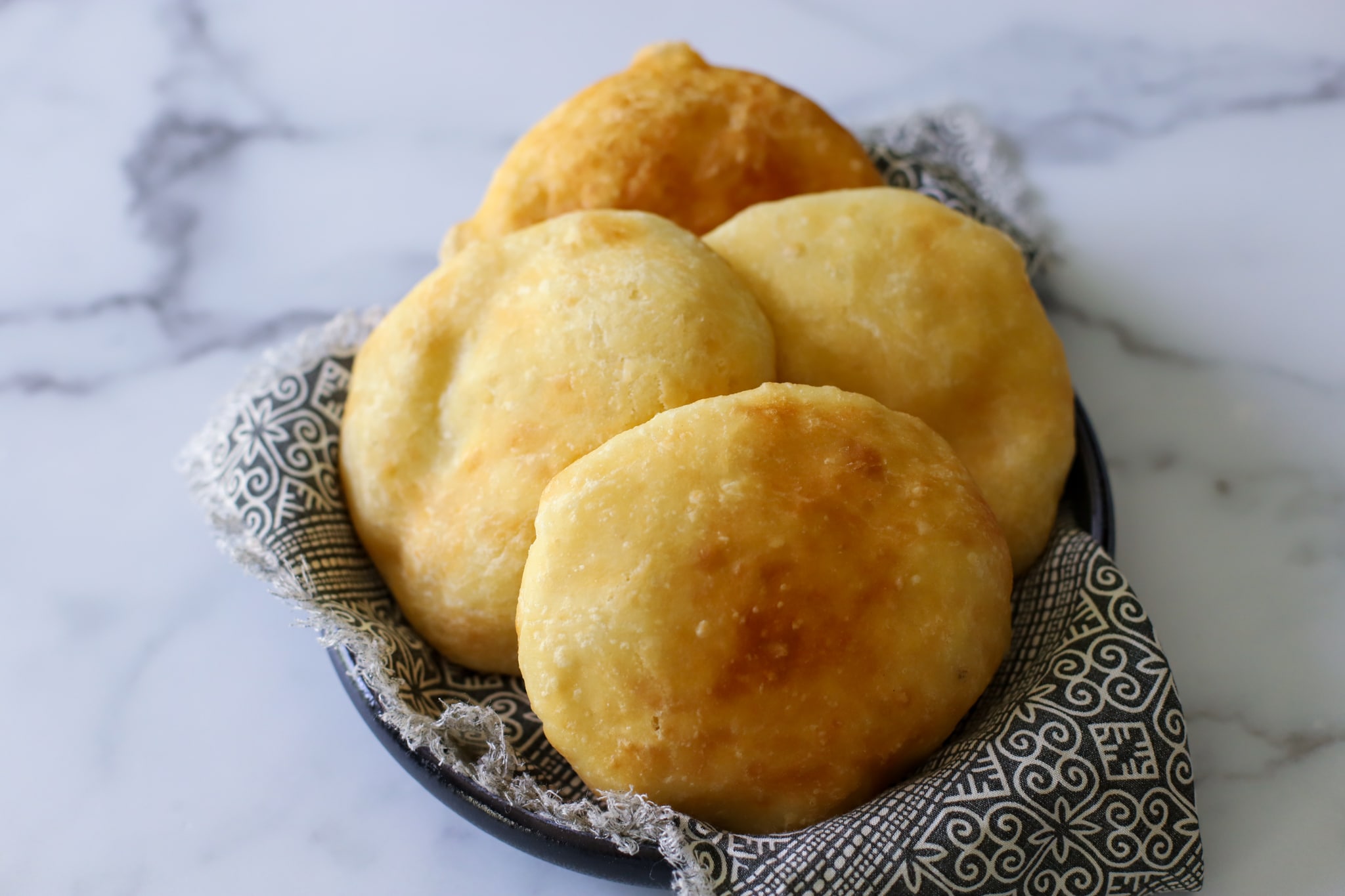 this photo shows 4 fried bakes golden brown and in a black and white decorative napkin
