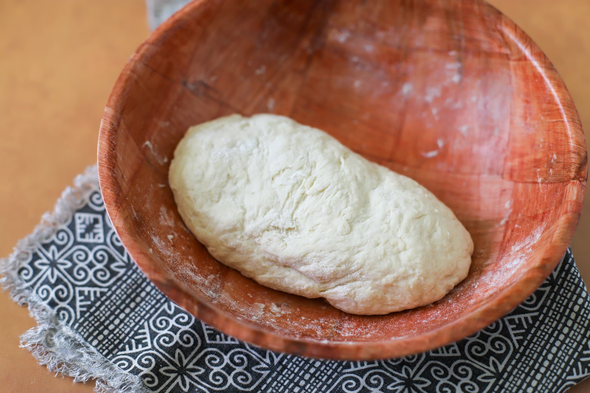 This photo shows a brown bamboo bowl with kneaded dough for bake in it