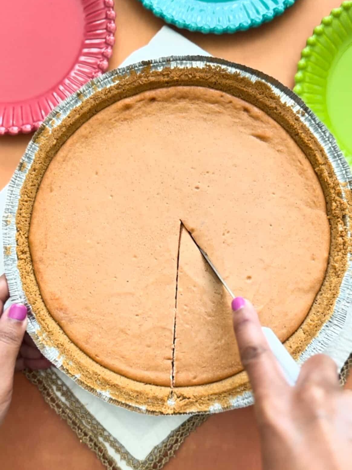 Guava cheesecake in a ready made graham cracker crust with a knife slicing the cheesecake