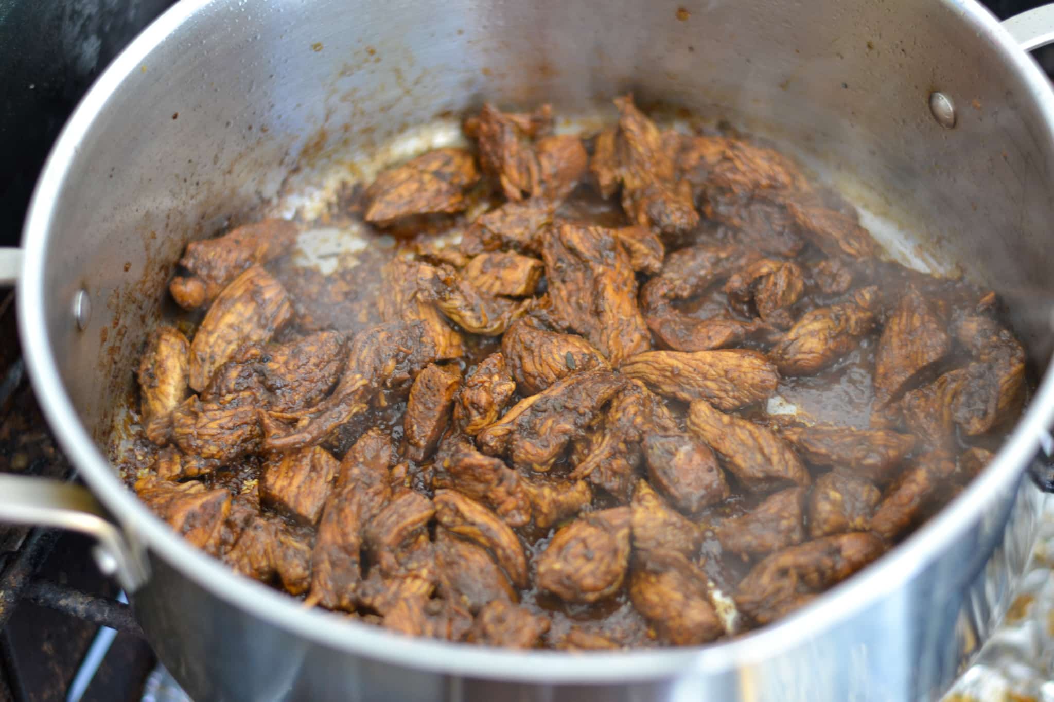 jerk chicken breasts being sauteed in pot