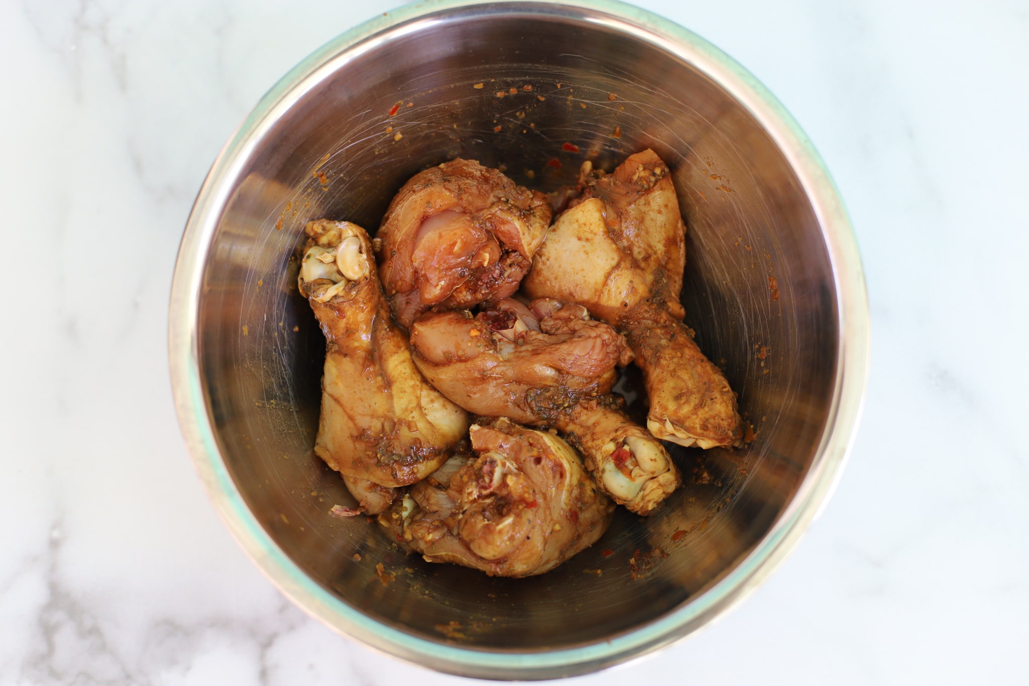 Chicken thighs in a metal bowl seasoned with caribbean green seasoning