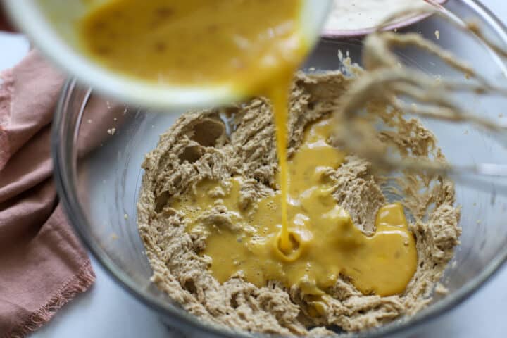 Beaten eggs being poured into cake batter for mixing later on