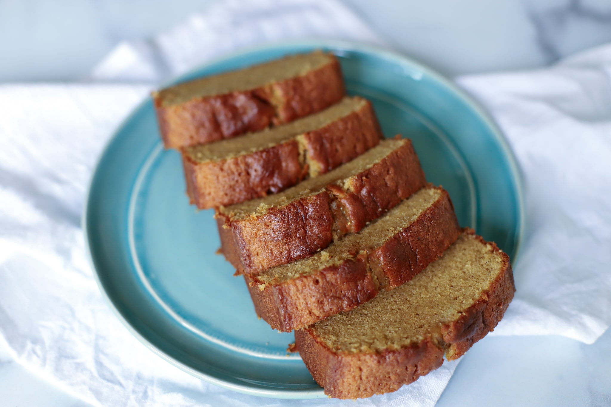 Five slices of sponge cake laid out on a blue plate on a white tablecloth