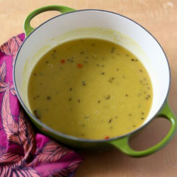 This is a pot of stovetop indo-caribbean style dhal it is in a green cast iron pot with a pink napkin next to it