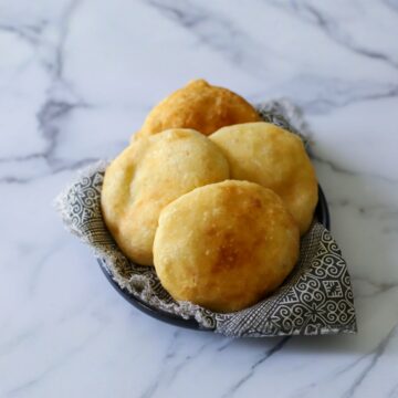 this photo shows 4 fried bakes golden brown and in a black and white decorative napkin