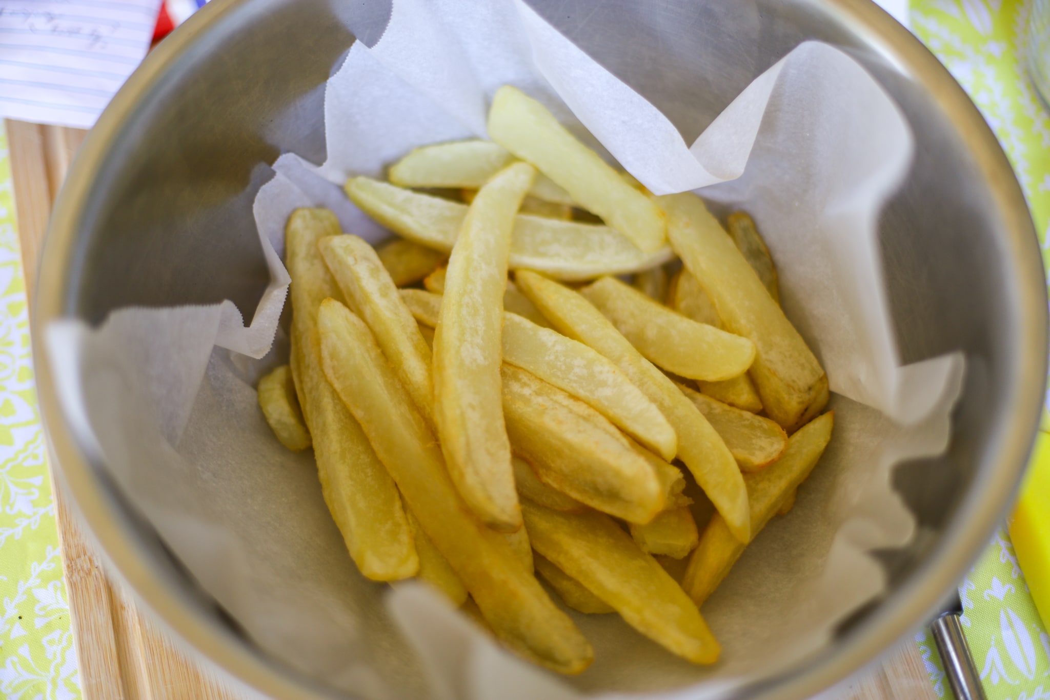 British chips in a silver bowl being drained in a silver bowl after the first fry