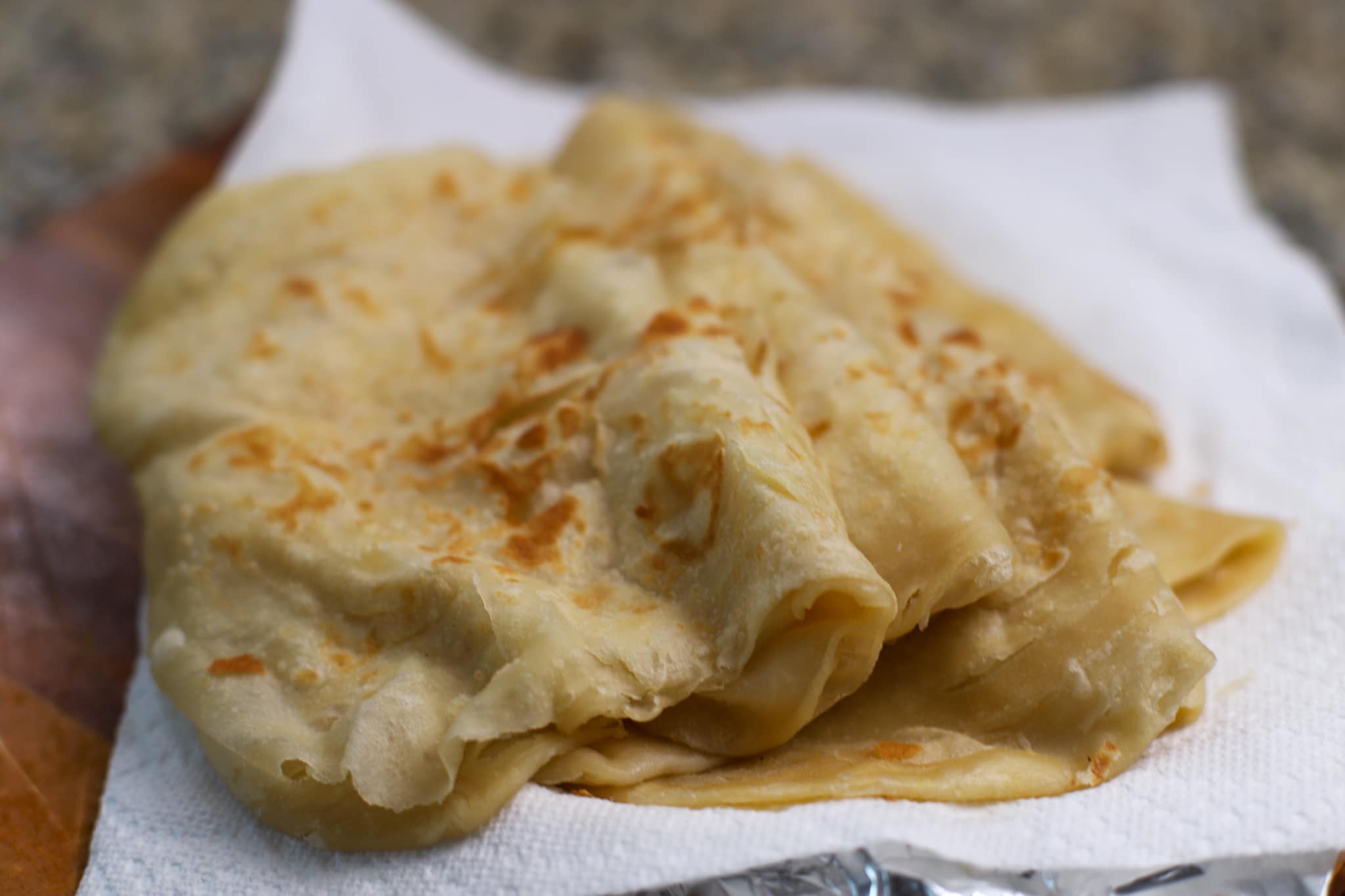 guyanese oil roti folded on a plate lined with paper towels
