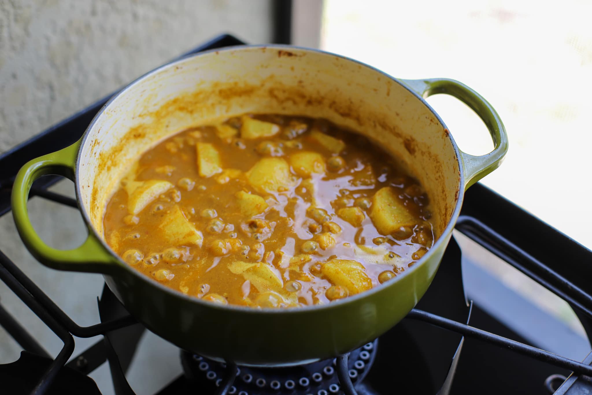 Guyanese channa curry in a green pot simmering on the stove